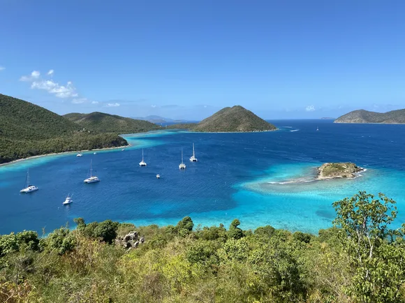 Distant boats dot turquoise water of varying shades on a brilliantly sunny day.
